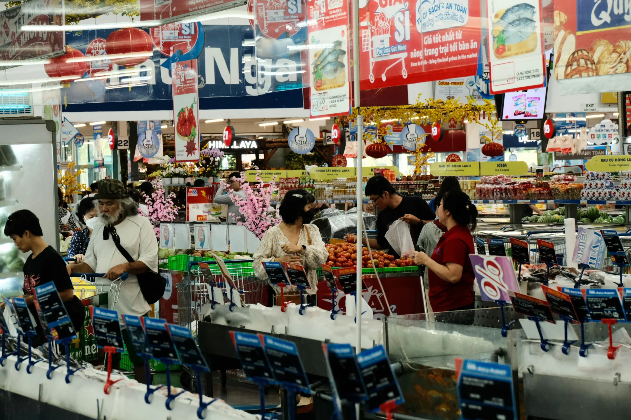 Zona de cajas en supermercado con clientes realizando pagos y compras, mostrando la interacción entre consumidores y el proceso de cobro.